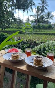 two cakes on plates on a wooden table at Citra Homestay in Tetebatu