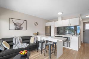 a kitchen and living room with a black couch at Central Location - 2 Bedroom Aptmt with Lake View in Queenstown +10 photos