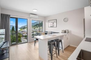 a kitchen with a counter with stools and a large window at Central Location - 2 Bedroom Aptmt with Lake View in Queenstown