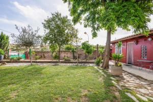 un cortile con una casa rossa e un albero di Cal Jaume a Masquefa