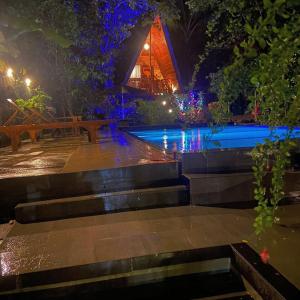 a swimming pool at night with a bench and a building at Levona Garden Resort in Habarana