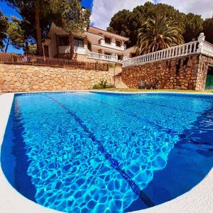 een groot blauw zwembad voor een huis bij Casa Blanca de La Sierra hasta 24 hasta personas con Piscina Salina y Bbq in Pelayos de la Presa