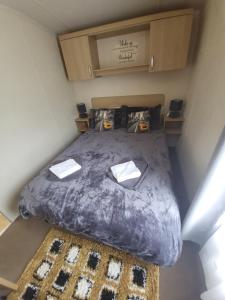 Dormitorio pequeño con cama con edredón púrpura en Caravan on the Devon\Cornwall border en Stratton