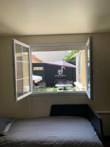 ein Fenster in einem Zimmer mit einem Bett und einem Truck in der Unterkunft Charmant Studio avec son jardin privé aux portes de Paris in Ivry-sur-Seine