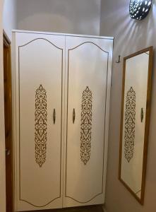 a white cabinet with stencils on it next to a mirror at Djerba Rêve Vacances Emna EL Beya in Midoun