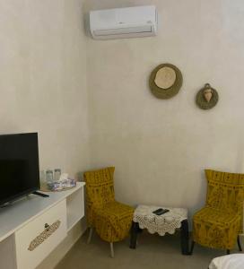 Zimmer mit 2 Stühlen und einem Schreibtisch mit einem TV in der Unterkunft Djerba Rêve Vacances Emna EL Beya in Midoun