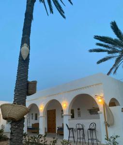 米多恩的住宿－Djerba Rêve Vacances Emna EL Beya，一座带椅子和棕榈树的建筑