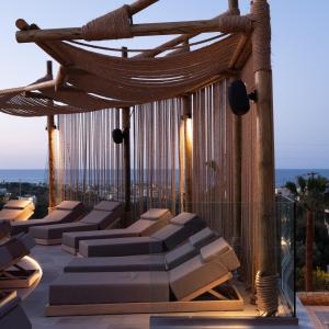a rooftop deck with chairs and a hammock at Asterias Village in Hersonissos