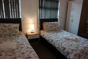 a bedroom with two beds and a lamp on a table at Cardoh Lodge in Blackpool