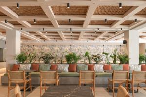 un vestíbulo con un banco largo con sillas y plantas en Sergios Hotel, en Hersonissos