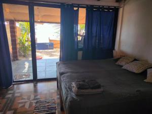 um quarto com uma cama com cortinas azuis e uma janela em Talpona Beach Studios em Magdāl