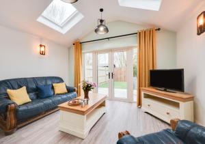 2 Wissett Cottages في Aldeby: غرفة معيشة مع أريكة زرقاء وتلفزيون