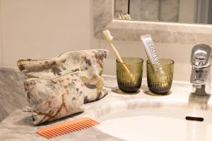 a bathroom counter with two cups and a toothbrush at Hôtel Le Lavoisier & Spa in Paris +41 photos