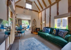 a living room with a green couch and a table at Lady Cottage in Lavenham