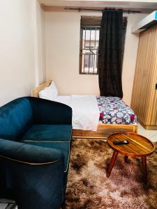 a bedroom with a bed and a couch and a table at Cottage chill in Kampala