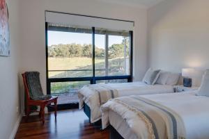 een slaapkamer met 2 bedden en een groot raam bij Old Coach Road Estate in Hindmarsh Valley