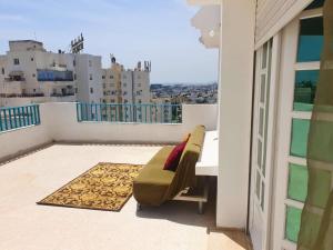 a balcony with a couch and a view of a city at Ennasr 2 - La Grande Terasse Vue Panoramique - Appartement Chaleureux - Chaines International - Barbeque - Fibre Internet & Navette in Ariana