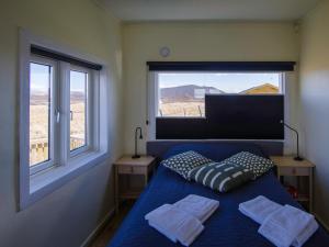 a bedroom with a bed with two pillows and two windows at Myvo The Studio apartment at Geiteyjarströnd 4 in Reykjahlíð