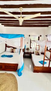 two beds in a room with a ceiling at Zava Nungwi in Nungwi