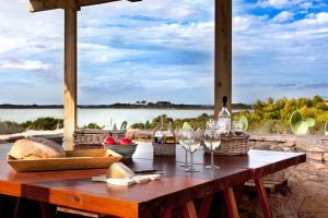 een picknicktafel met wijnglazen en uitzicht op het water bij Cas Saliners - Villa Can Paya in La Savina