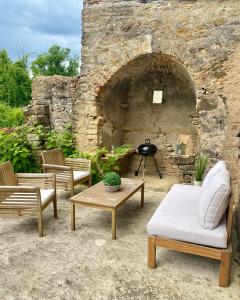 un patio avec deux chaises et une table et un mur en pierre dans l'établissement L'écrin, charmant cottage aux portes de la cité médiévale de Semur-en-Auxois, à Chevigny