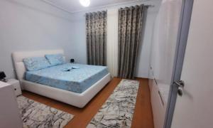 a bedroom with a bed with blue sheets and curtains at Vila Seitaj in Sarandë