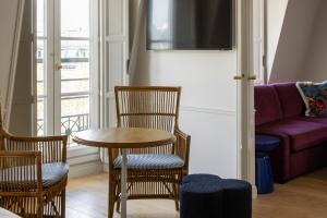 ein Wohnzimmer mit einem Tisch, Stühlen und einem Sofa in der Unterkunft Hôtel Le Lavoisier in Paris