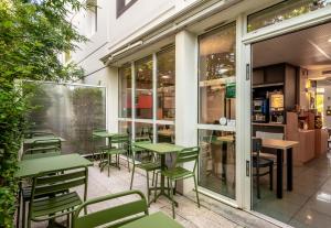 um restaurante vazio com mesas e cadeiras verdes em B&B HOTEL Béziers em Béziers