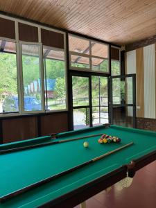 a pool table in a room with windows at Chalet Rivier • შალე რივიერ in K'eda