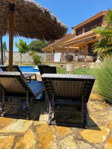 two chairs and an umbrella next to a pool at Casa rural Las Vegas in Pelayos de la Presa