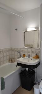 y baño con bañera, lavabo y espejo. en Cabourg Plage, en Cabourg