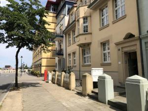 a building on the side of a street with a tree at Warnemuender-Strandjuwel in Warnemünde