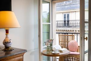 Zimmer mit einem Tisch mit einer Lampe und einem Fenster in der Unterkunft Hôtel Le Lavoisier in Paris