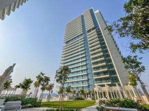 een hoog gebouw met palmbomen ervoor bij CitiHome-3BR Marina with beach view in Dubai