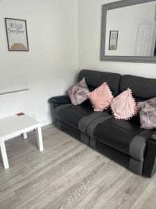 a black couch with pillows in a living room at Largs Apartment, Spacious & Modern 1 Bed near beach & shops in Largs