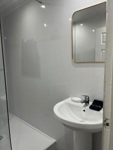 een witte badkamer met een wastafel en een spiegel bij Largs Apartment, Spacious & Modern 1 Bed near beach & shops in Largs