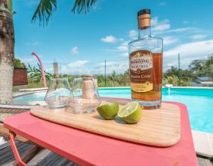 a bottle of whiskey and two glasses and a lime at Au son des Grenouilles in Sainte-Rose