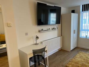 a white desk with a chair and a television on a wall at Luxury Studio Apartment in Luton