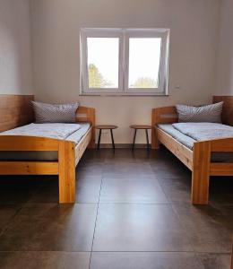 two beds in a room with a window and two tables at Eibauer Apartments in Sinsheim