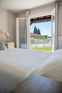 a bedroom with a bed and a large window at le Relais des Tuileries in Séreilhac