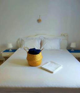 a basket sitting on top of a white bed at Georgia Rooms Milos in Plaka Milou