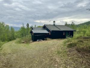 uma pequena casa preta no meio de um campo em Koselig familiehytte ved Bardola em Geilo