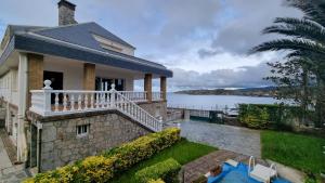a house with a balcony and a body of water at Playa de Comillas in Comillas +4 photos