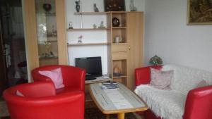 ein Wohnzimmer mit 2 roten Stühlen, einem Tisch und einem TV in der Unterkunft Josy's Holiday & Business Apartment in Sarnen