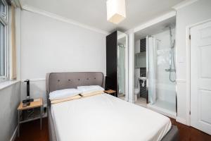 ein Schlafzimmer mit einem weißen Bett und einer Dusche in der Unterkunft A Charming 1BR apartment in Bromley in Bromley