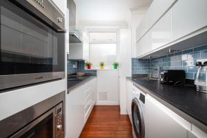 a kitchen with white cabinets and a washer and dryer at A Charming 1BR apartment in Bromley in Bromley