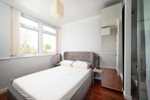una camera da letto con un grande letto bianco con due cuscini di A Charming 1BR apartment in Bromley a Bromley