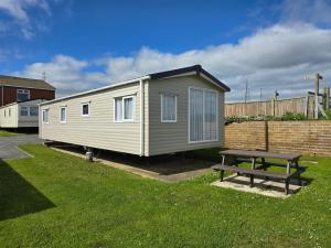 a tiny house with a picnic table in a yard at Castaways Holiday Park in Bacton