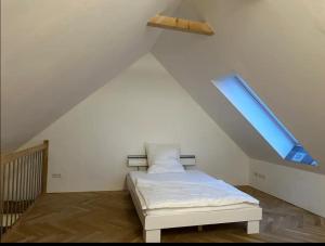 Un dormitorio con una cama en un ático con ventana. en Exklusive Maisonetten Wohnung mit Gartenzugang, en Augsburg
