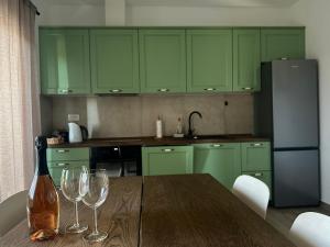 a kitchen with green cabinets and a table with wine glasses at Apartment Giò in Tar